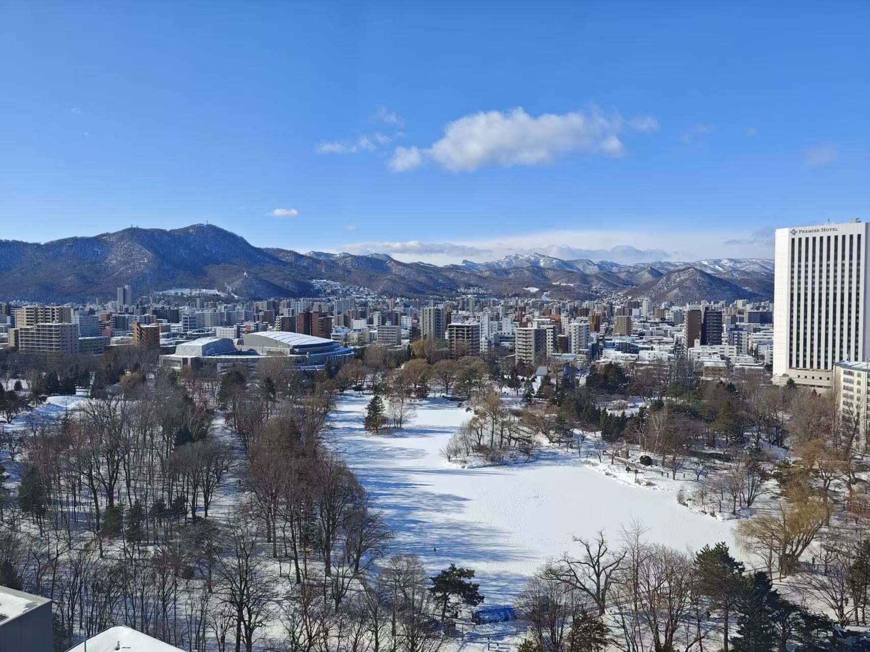 Snow-covered Sapporo and mountains under a blue sky