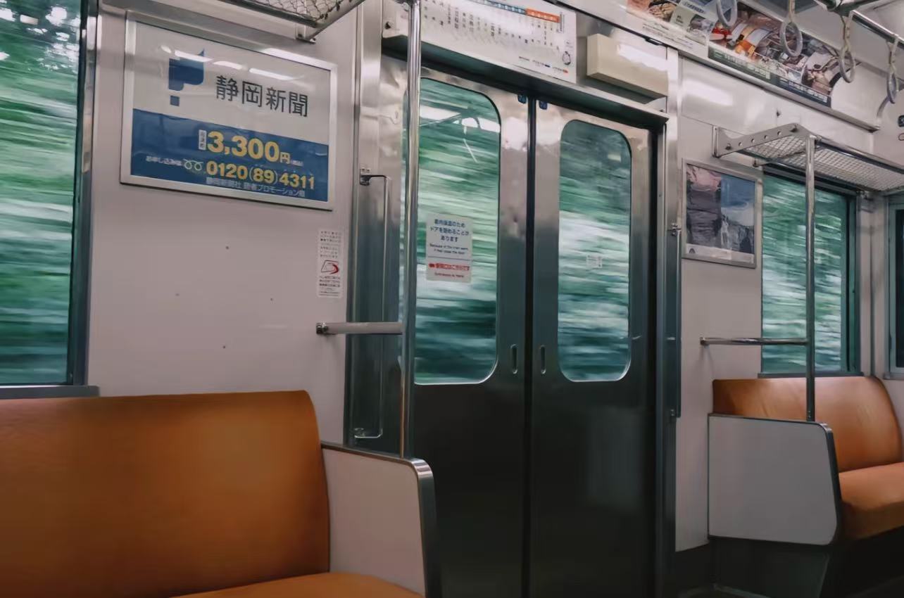 An empty Tokyo train carriage with greenery moving past its windows